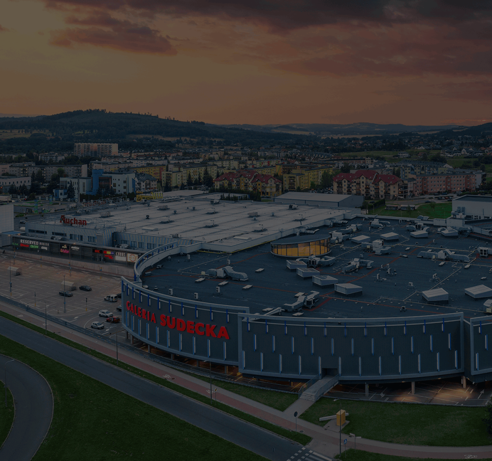 Widok z lotu ptaka na budynek Galerii Sudeckiej z piekną panormą w tle i zachodzącym słońcem.